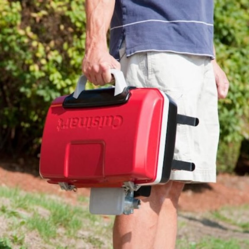Person carrying portable red Cuisinart grill.