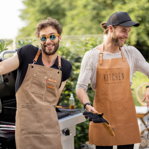 Two men smiling beside a barbecue.