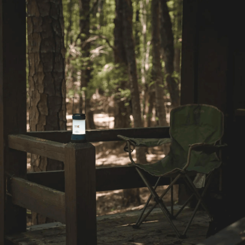 Camping chair and lantern on a wooden porch.