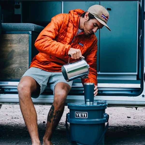 Man pouring coffee outdoors by a van.